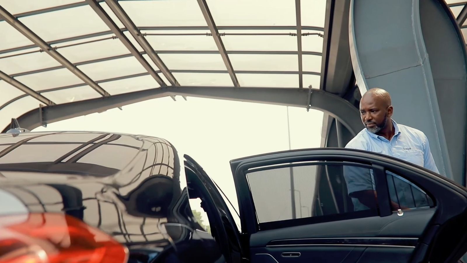 PTL chauffeur opening the rear door of a black executive car