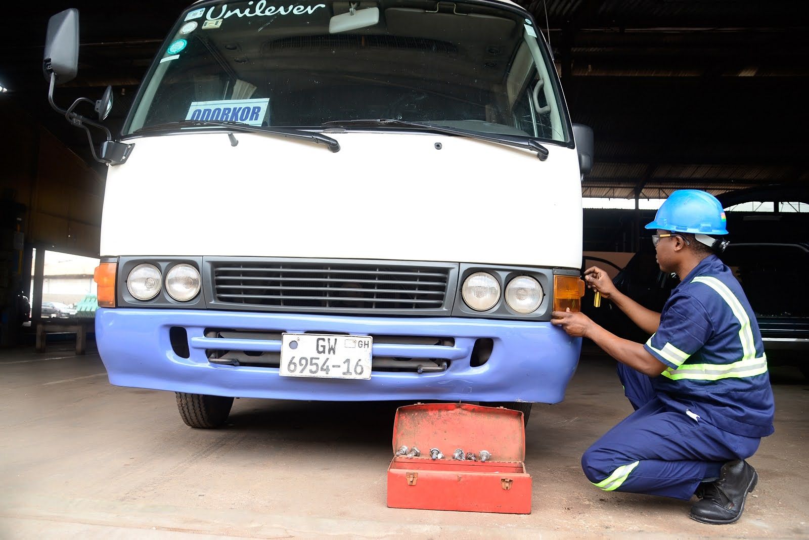 PTL technician in hard hat and hi-vis checking the lights on a staff bus